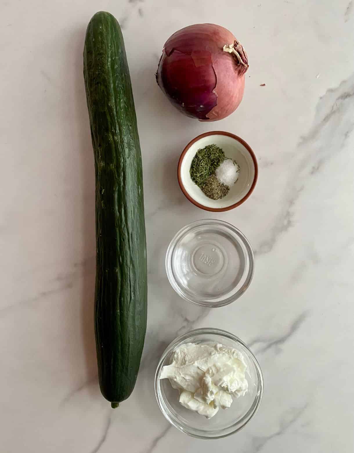 A cucumber, a red onion, white vinegar, sour cream, salt, pepper and dill.