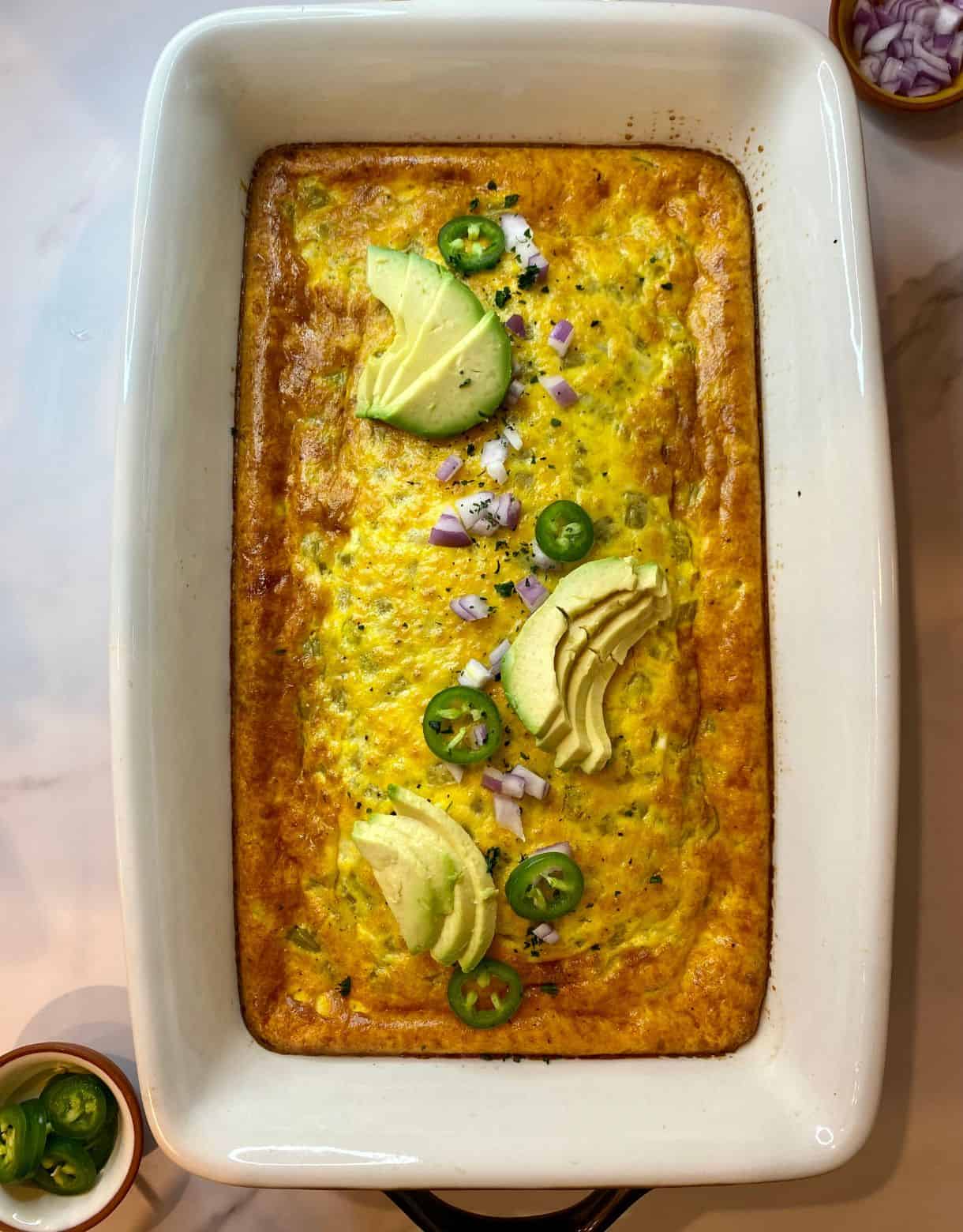 Green Chile Egg Casserole in a pan with sliced avocado on top.