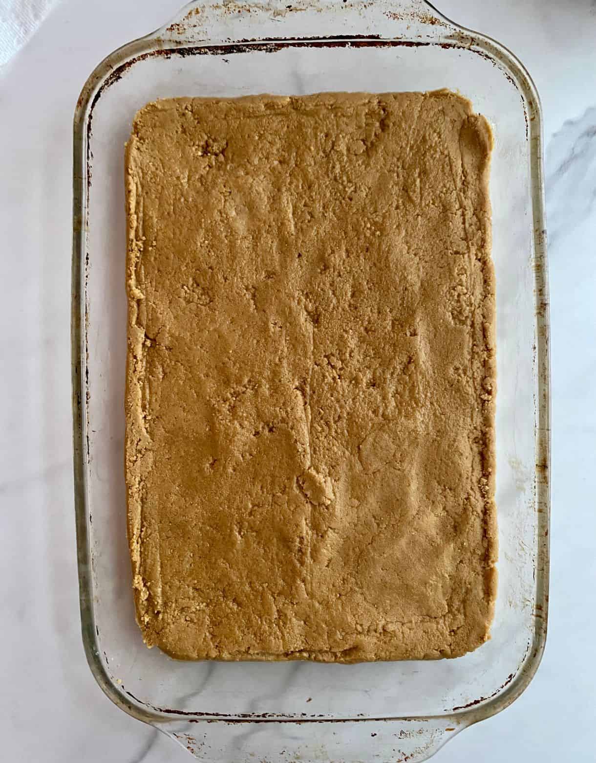 A pan with the peanut butter dough spread flat for No-Bake Chocolate Peanut Butter Bars.