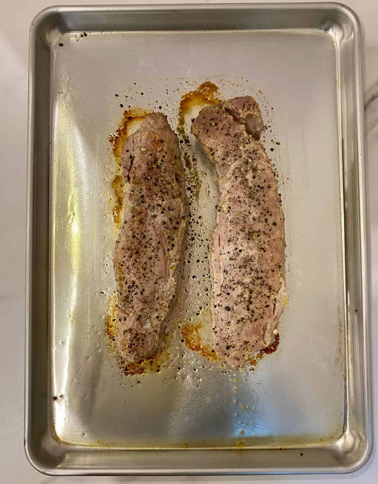 Two cooked pork tenderloins on a sheet pan.