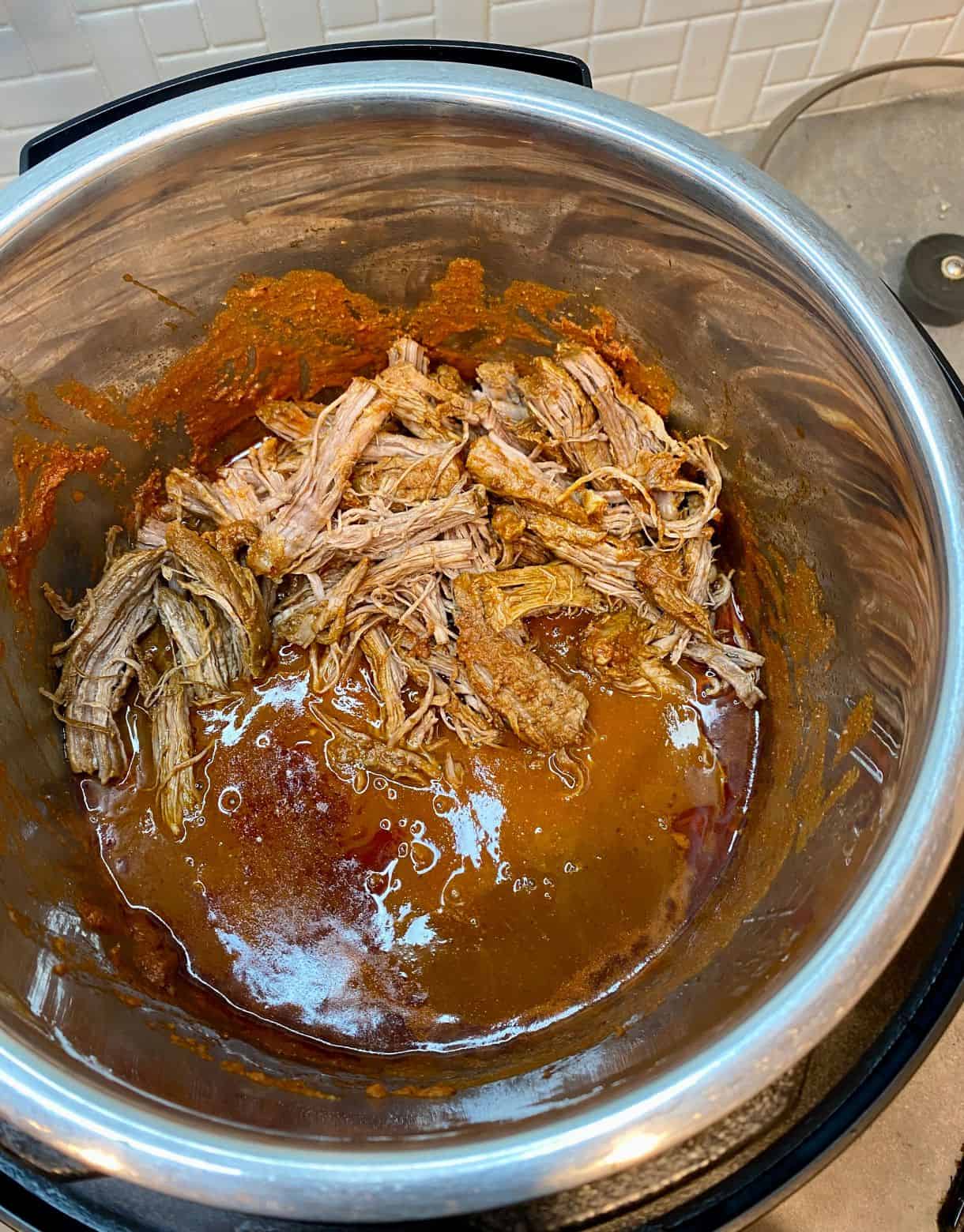 Slow cooker with shredded beef and sauce for Pulled Beef Tacos.