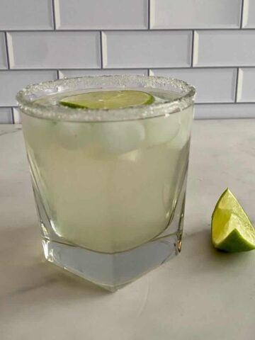 A Coconut Water Cocktail in a glass with a wedge of lime.