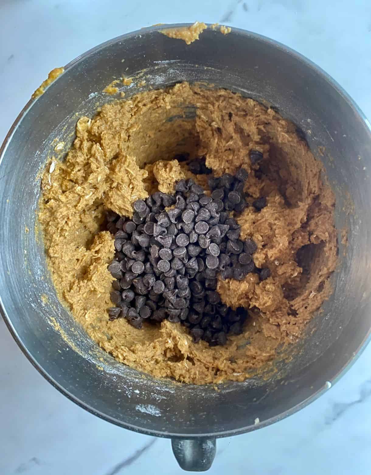 A mixing bowl with batter for Healthy Pumpkin Chocolate Chip Muffins with the chocolate added but not stirred.