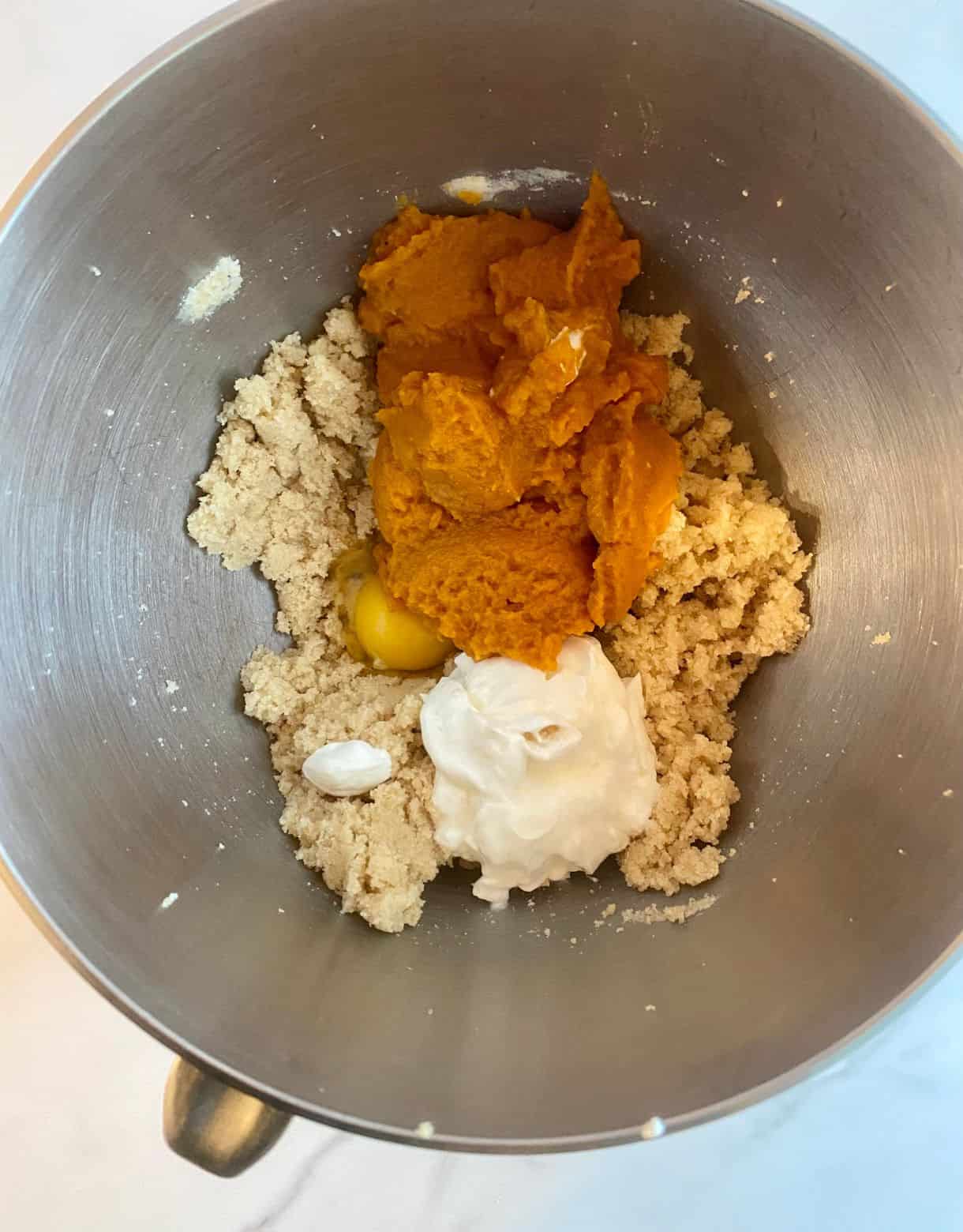 A mixing bowl with the wet ingredients for Healthy Pumpkin Chocolate Chip Muffins added but not mixed.