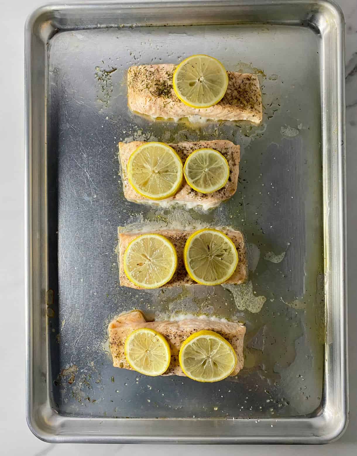 A sheet pan with cooked Baked Salmon with Dill and Lemon.