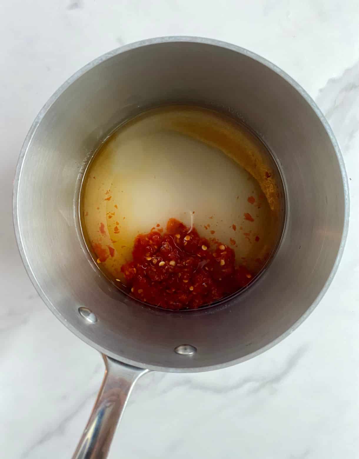 A small pot with the ingredients for sweet chili sauce added but not stirred.