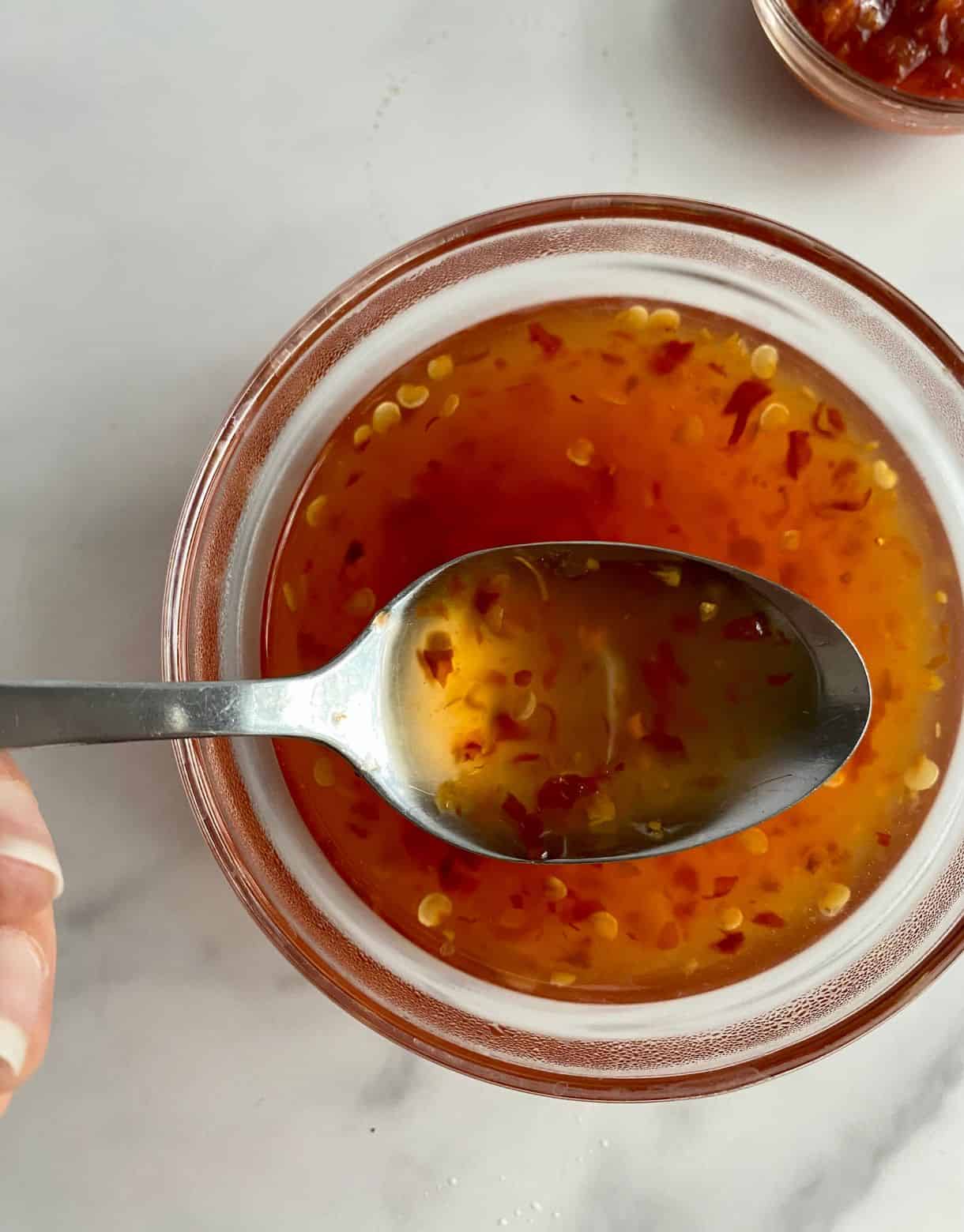 A bowl of Sweet Chili Sauce with a spoon.