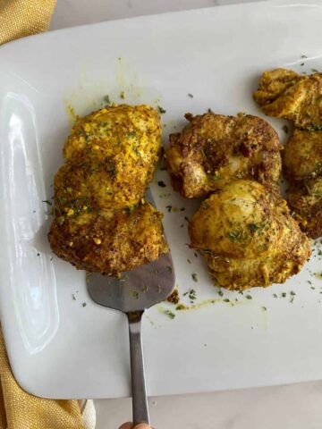 A platter with 3 cooked Garam Masala Chicken Thighs.