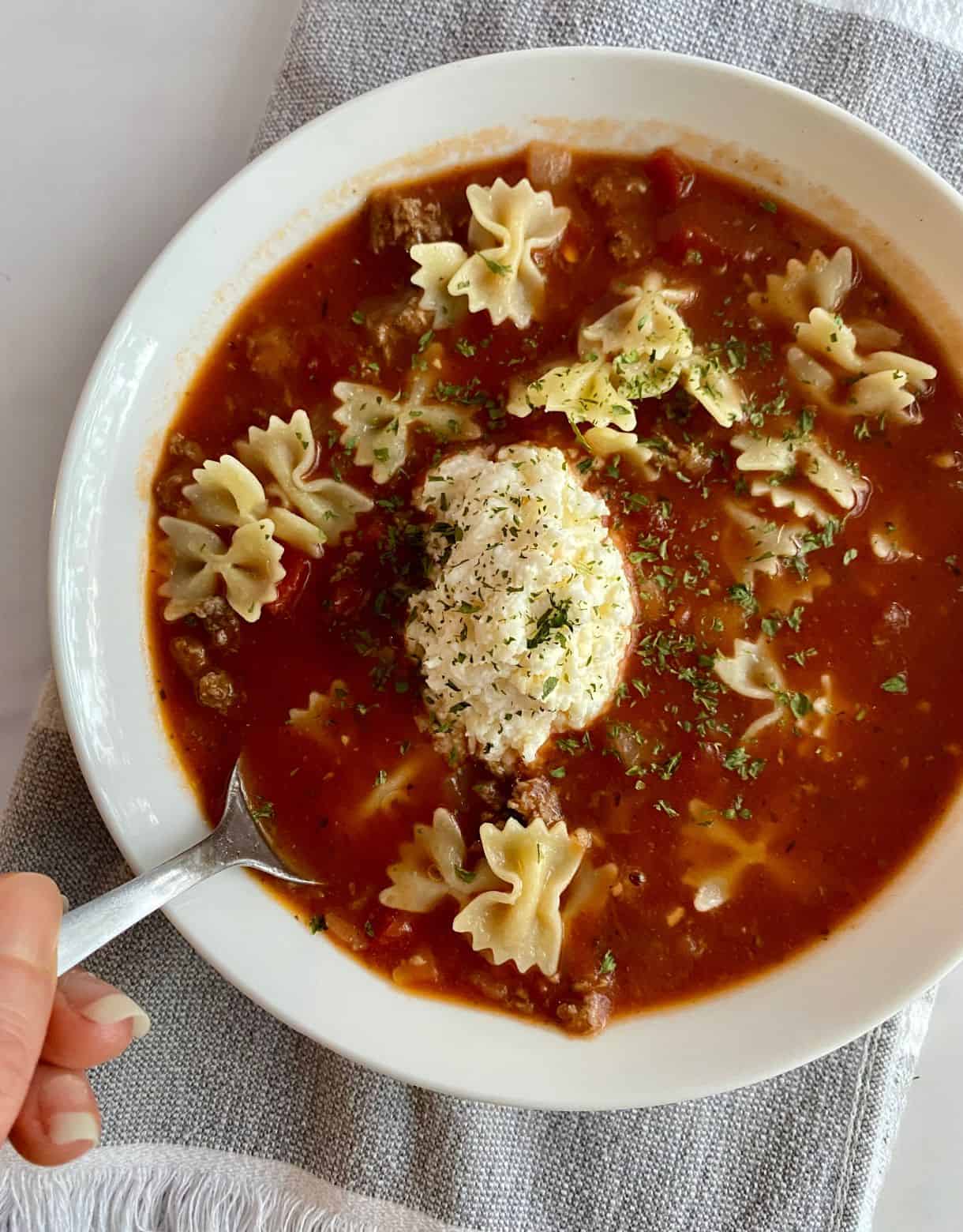 A bowl of Healthy Lasagna Soup with a dollop of cheese.