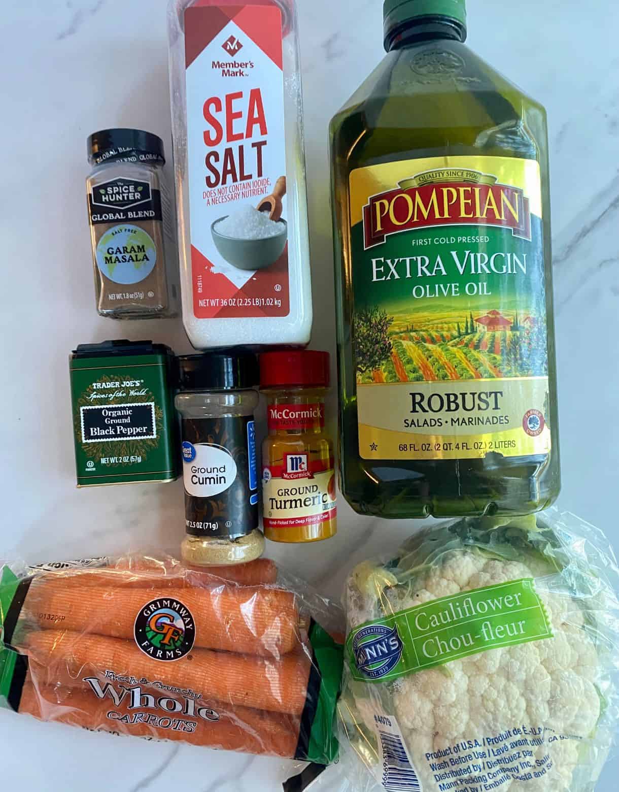 Olive oil, a bag of carrots, a head of cauliflower, turmeric, cumin, garam masala, salt and pepper.