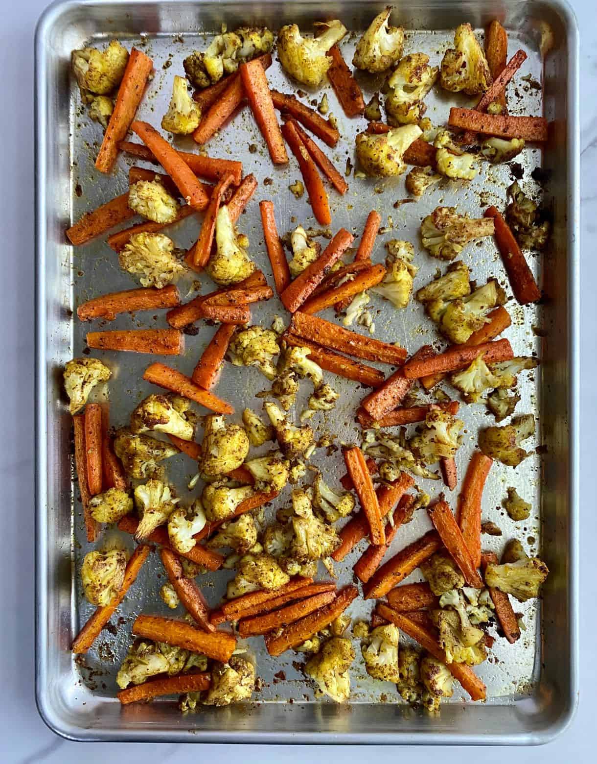 A sheet pan with cooked cauliflower and carrots on it.