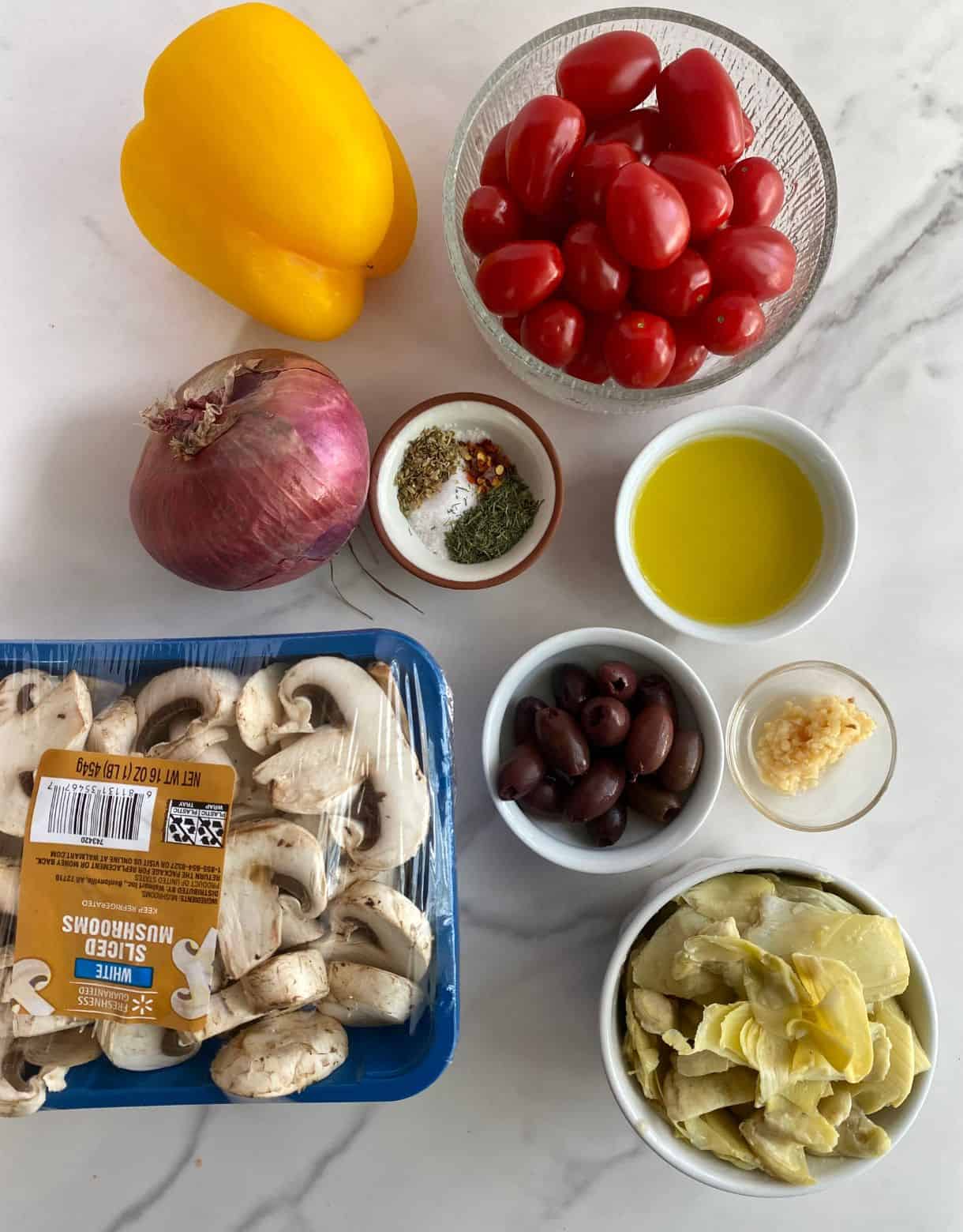 Ingredients for Mediterranean Roasted Vegetables. Grape tomatoes, bell pepper, red onion, salt, pepper, herbs, olive oil, minced garlic, olives, mushrooms and artichoke hearts.