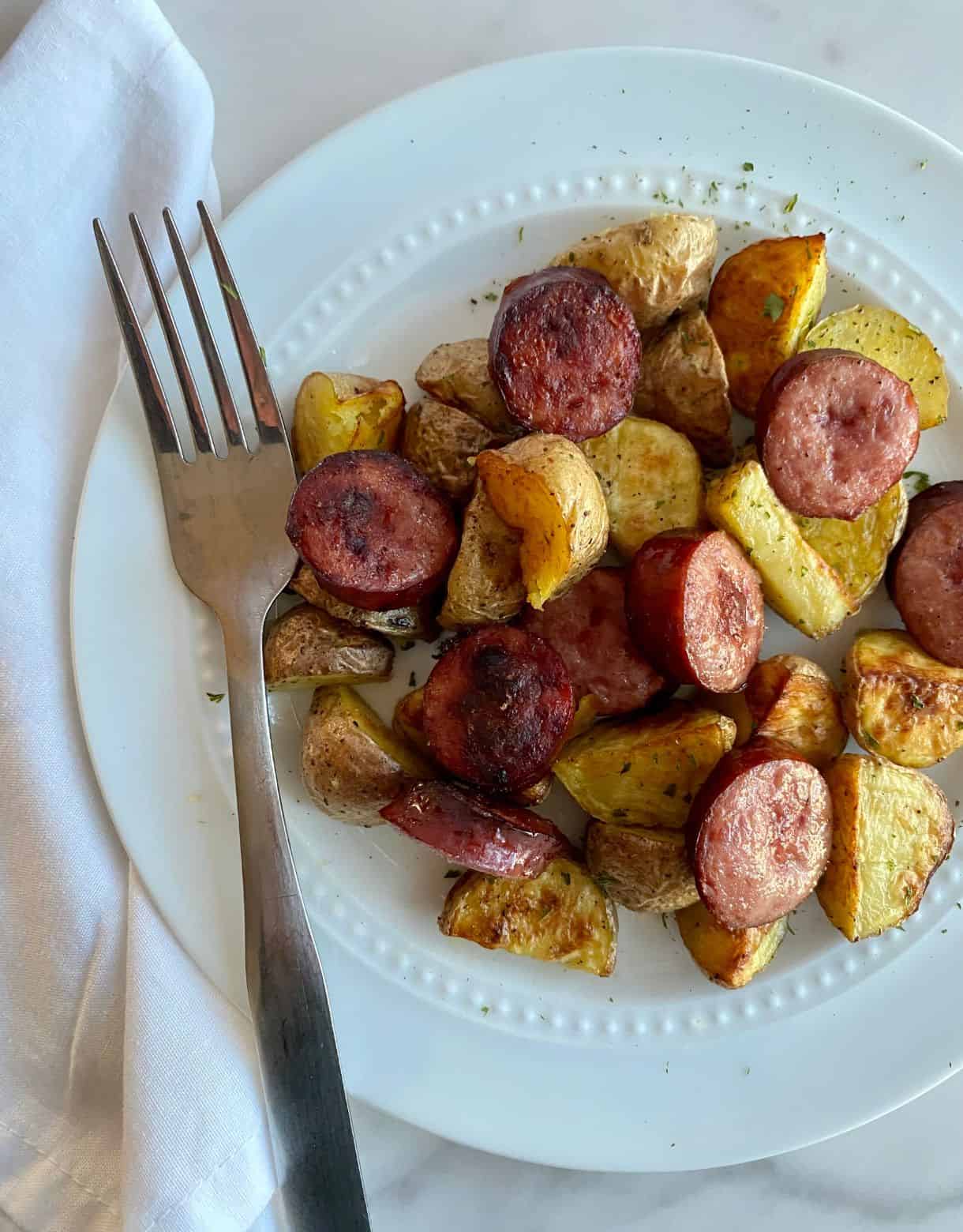 A plate of oven roasted smoked sausage and potatoes.