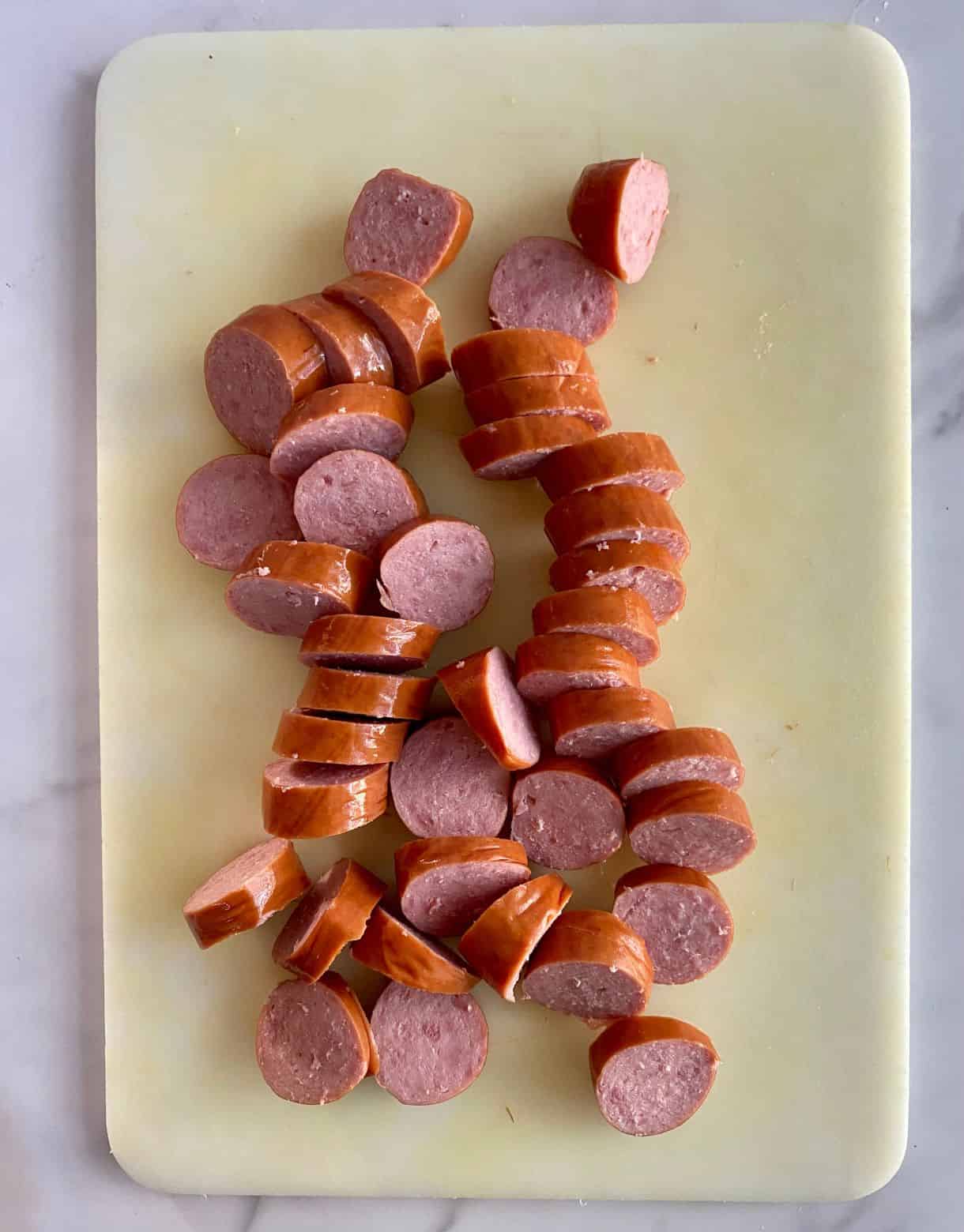 A cutting board with sliced smoked sausage.