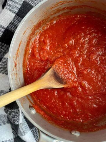 A pot of Spicy Marinara Sauce with a wooden spoon in it.