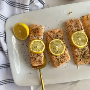 A platter with cooked Baked Salmon with Dill and Lemon.