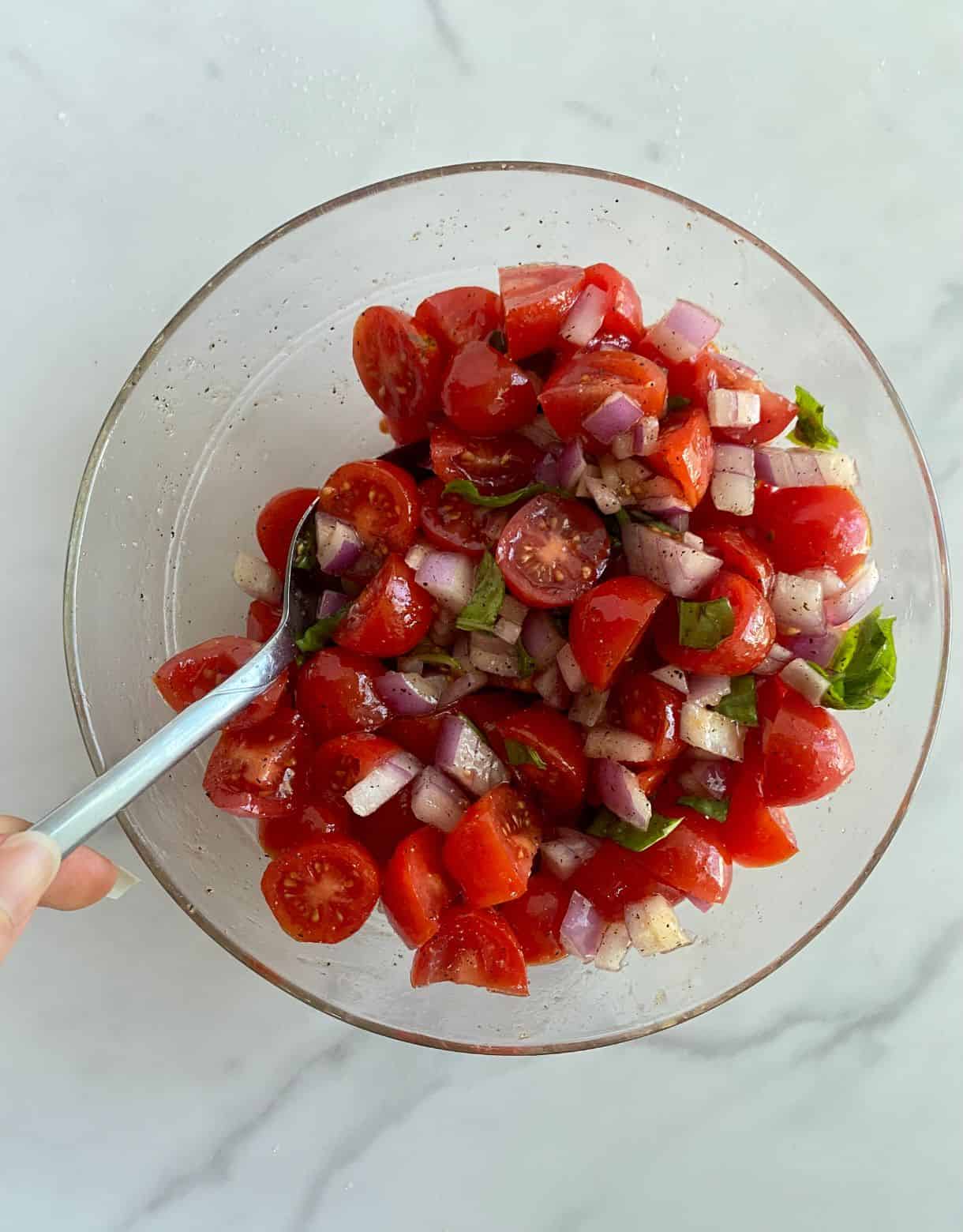 A bowl of mixed Bruschetta Dip with chopped tomatoes, onion, basic and garlic.