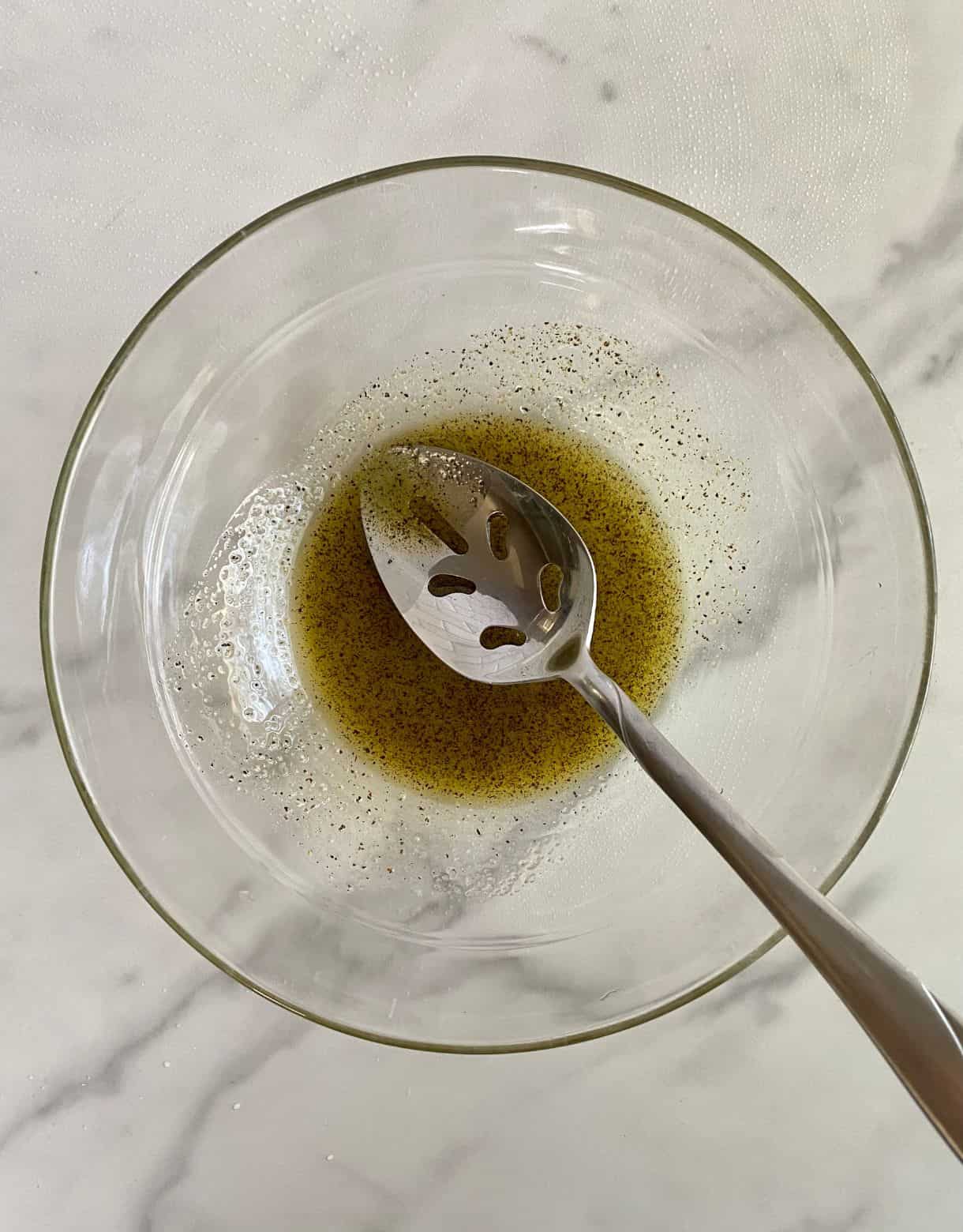 A bowl of olive oil, salt and pepper stirred together.