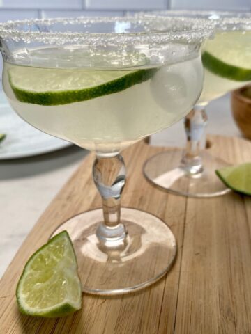 Two glasses of Cointreau Margaritas with a salted rim and lime wheels.