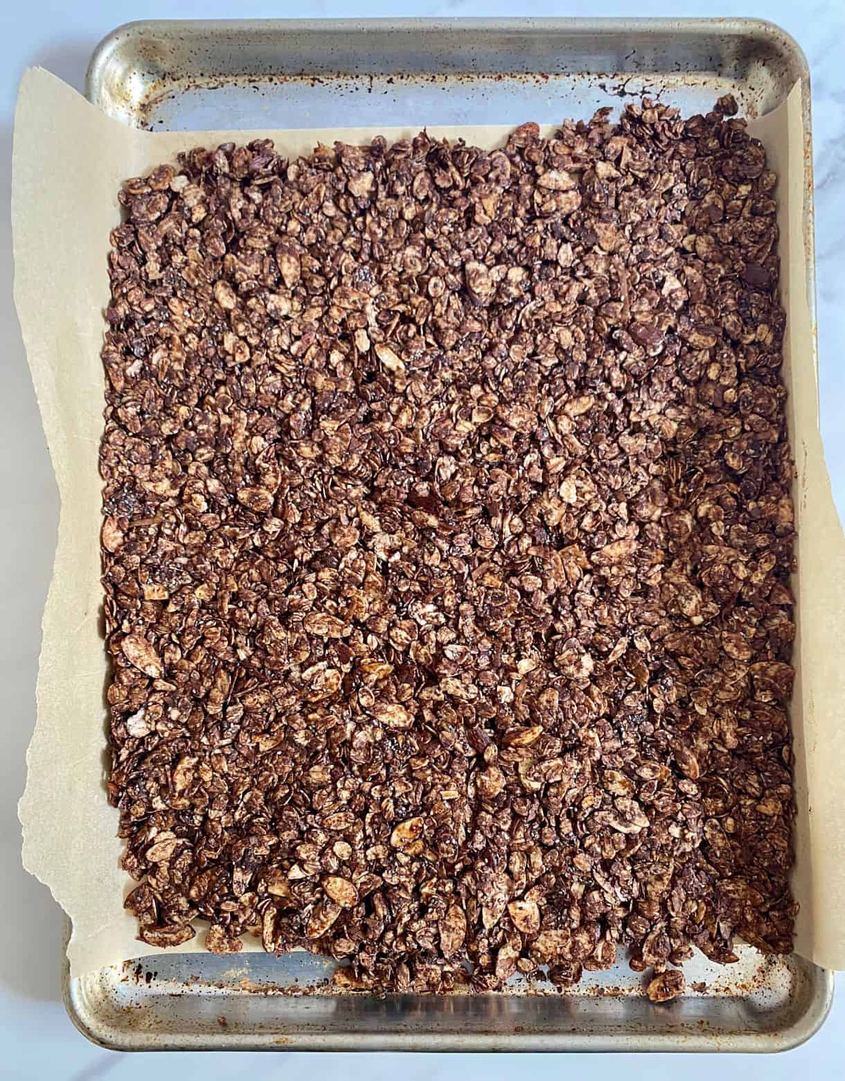 A sheet pan with Dark Chocolate Granola spread on it ready to go in the oven.