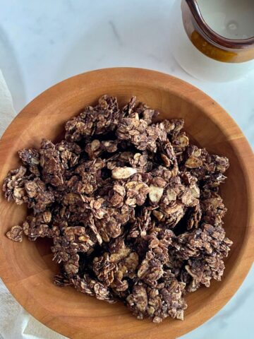 A bowl of Dark Chocolate Granola and a pitcher of almond milk.