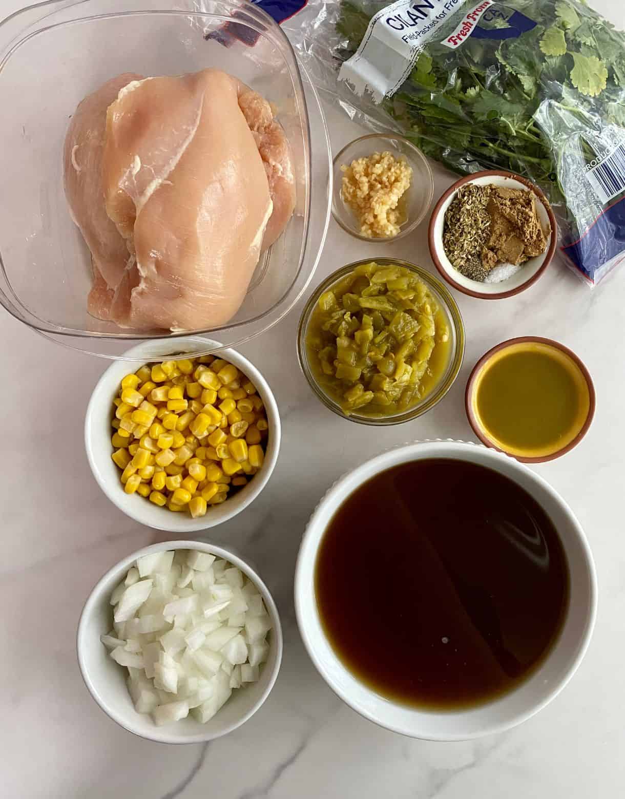 Ingredients for Green Chile Chicken Soup. Chicken breasts, chicken broth, corn, diced onion, diced green chiles, garlic, jalapeno hot sauce, salt, cumin, oregano, pepper and cilantro.