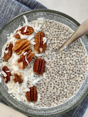 A bowl of Keto Chia Pudding topped with nuts and shredded coconut.