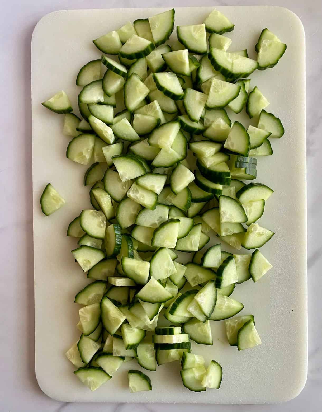A cutting board with chopped cucumbers.