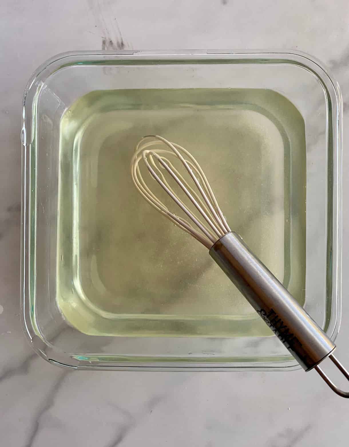 A dish with vinegar, salt and sugar added to it with a whisk.