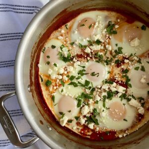 A pot with cooked Turkish Shakshuka topped with feta cheese and cilantro.