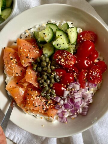 A Savory Cottage Cheese Bowl with cottage cheese, smoked salmon, diced cucmbers, sliced tomatoes, diced red onion, capers and Everything but the Bagel Seasoning.