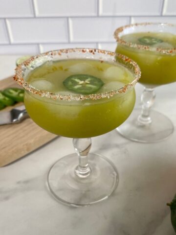 Two glasses of skinny spicy margarita with a salted rim and a jalapeno slice floating in the cocktail.