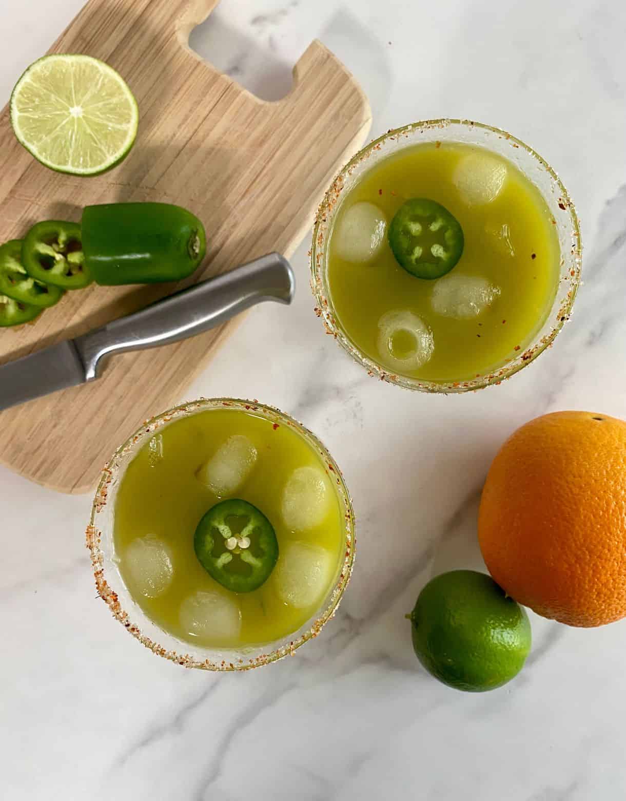Two glasses of skinny spicy margarita with a salted rim and a jalapeno slice floating in the cocktail.