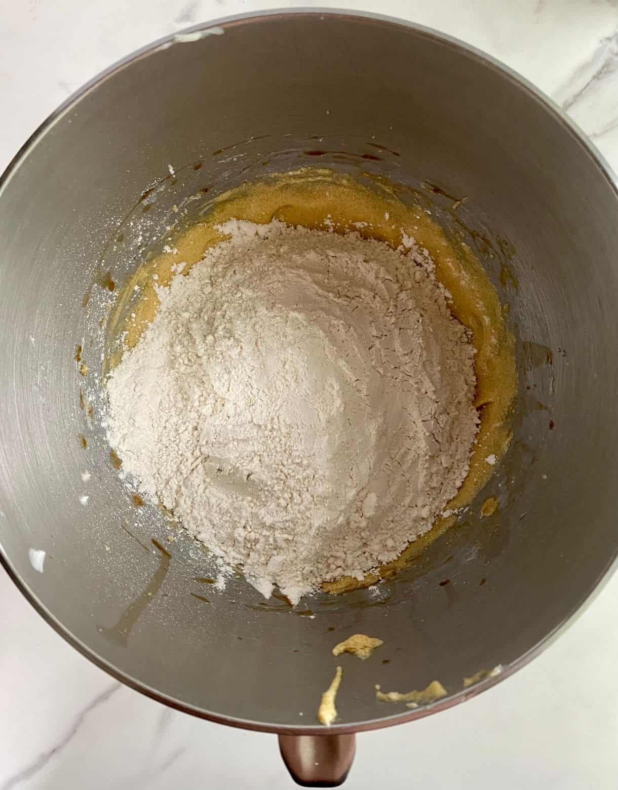A bowl with creamed butter and sugar with flour added but not stirred.