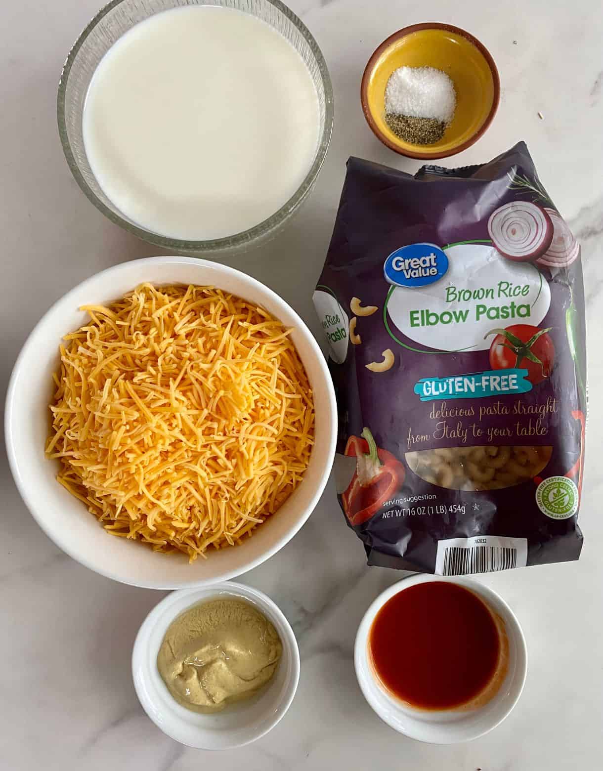 Ingredients for gluten-free mac and cheese. Elbow pasta, shredded cheddar cheese, milk, salt, pepper, hot sauce and dijon mustard.