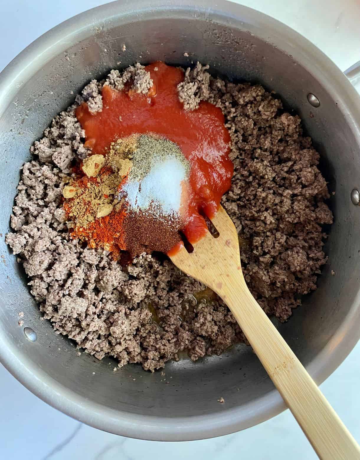 A skillet with ground beef with seasonings added but not yet stirred.