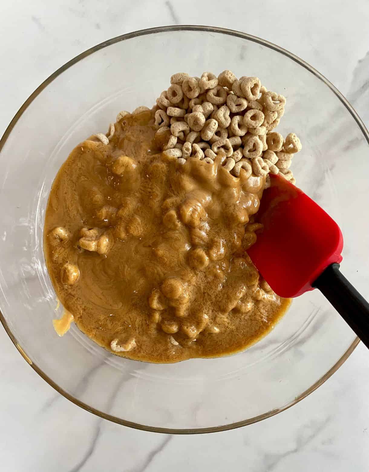 A bowl ot Cheerios with peanut butter honey mixture added but not stirred.