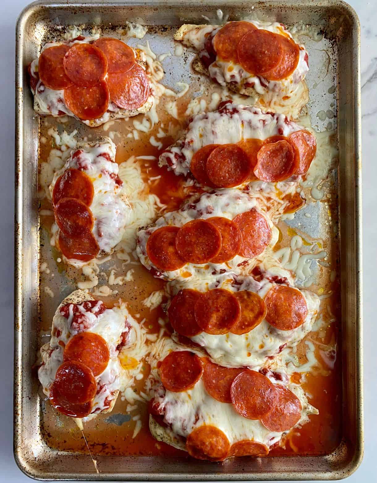 A sheet pan with cooked Pepperoni Pizza Chicken.