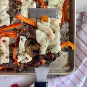 A sheet pan with cooked Philly Cheesesteaks.