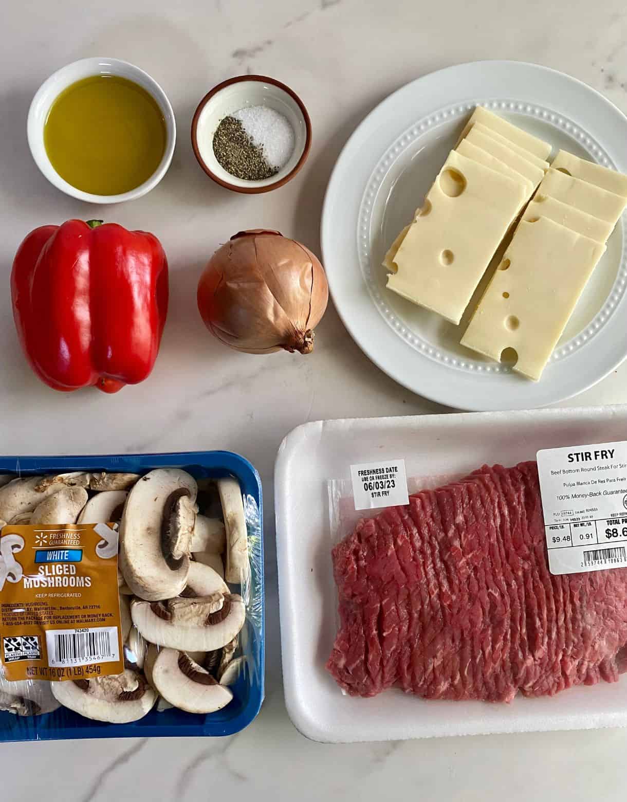 Ingredients for Sheet Pan Philly Cheesesteaks. Sliced mushrooms, sliced beef, sliced Swiss cheese, an onion, a bell pepper, olive oil, salt and pepper.