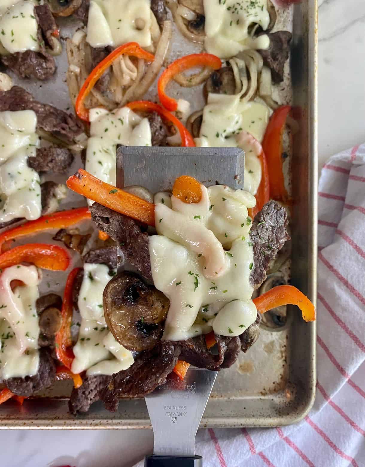 A sheet pan with cooked Philly Cheesesteaks.