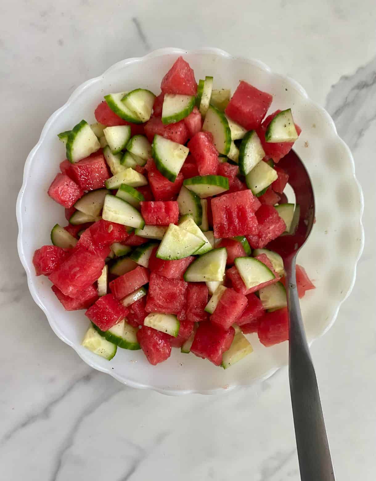 A bowl with chopped watermelon and cucumber stirred together.