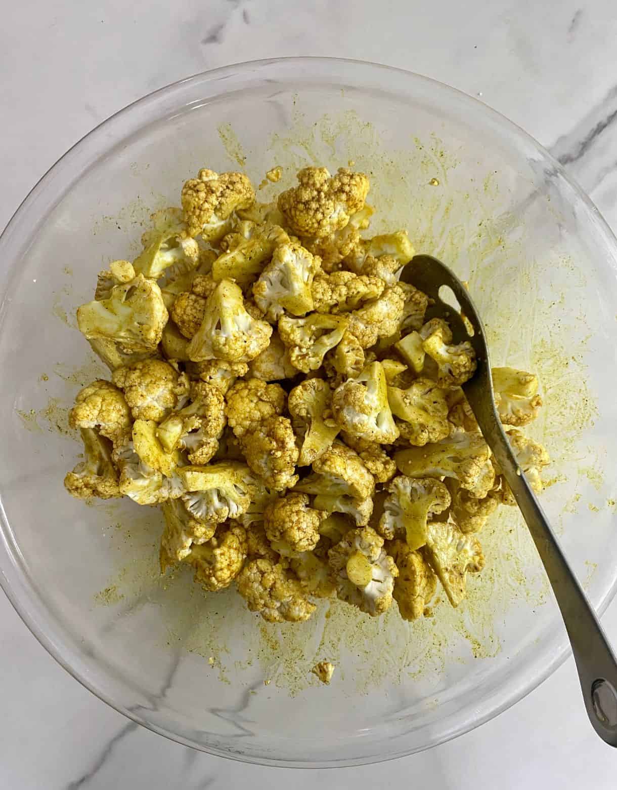 A bowl of cauliflower coated in oil and spices.