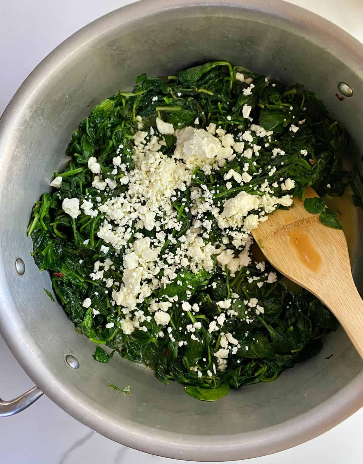A pan with cooked spinach and feta.