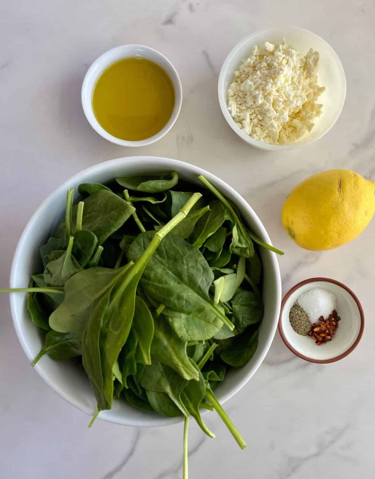 Raw spinach, crumbled feta cheese, olive oil, a lemon, salt, pepper and red pepper flakes.