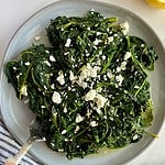 A plate with cooked spinach and feta.
