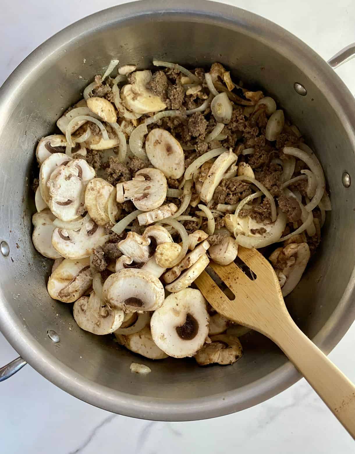 A pot of sauteeing turkey sausage, mushrooms and onions.