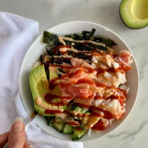 A Deconstructed Sushi Bowl with cauliflower rice, crab, avocado, cucumbers, seaweed, pickled ginger and sriracha mayo.