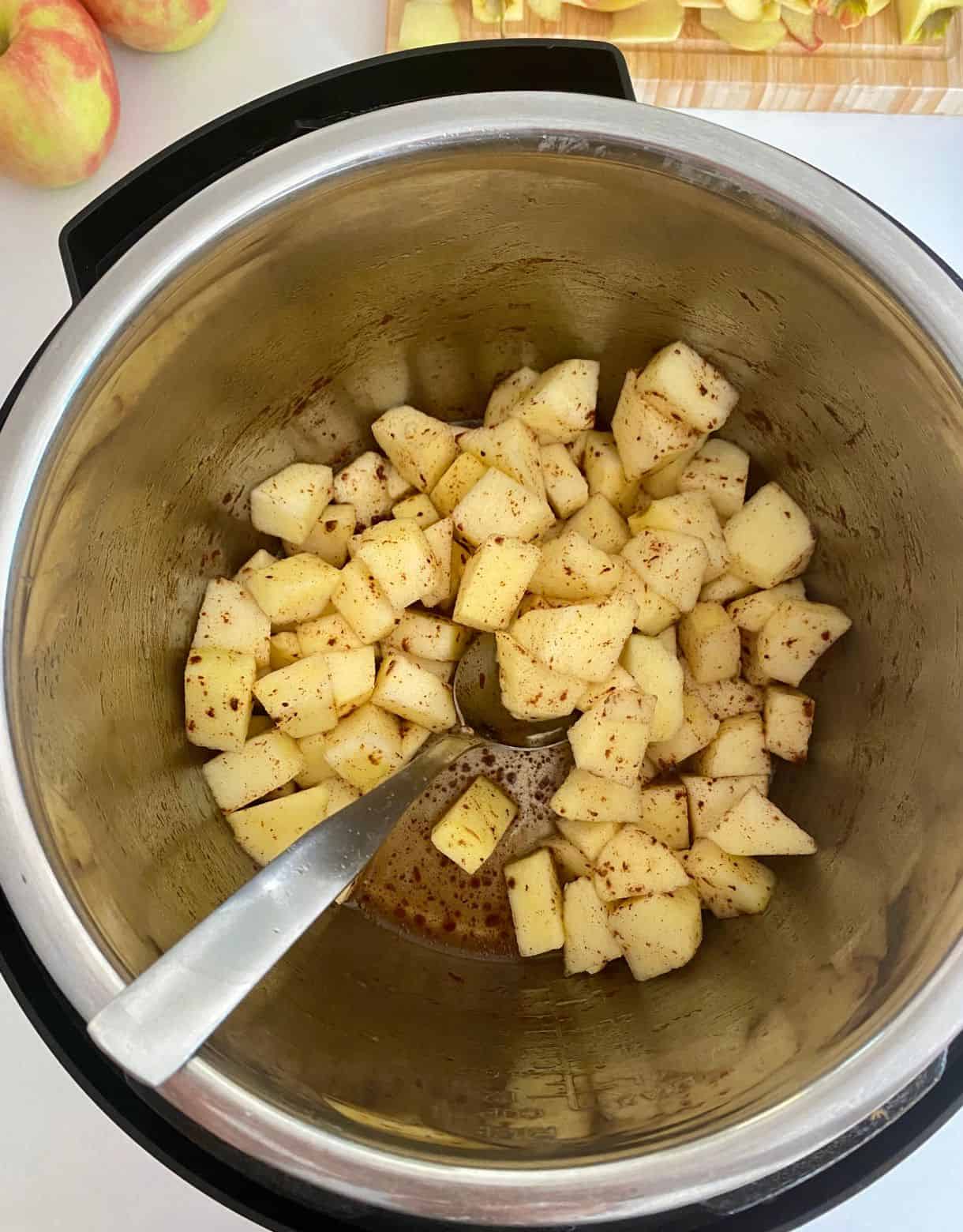 A slow cooker with diced apples and cinnamon.